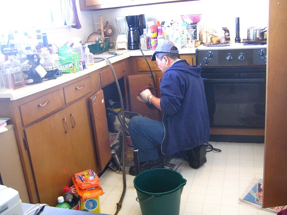 A plumber working under a kitchen sink